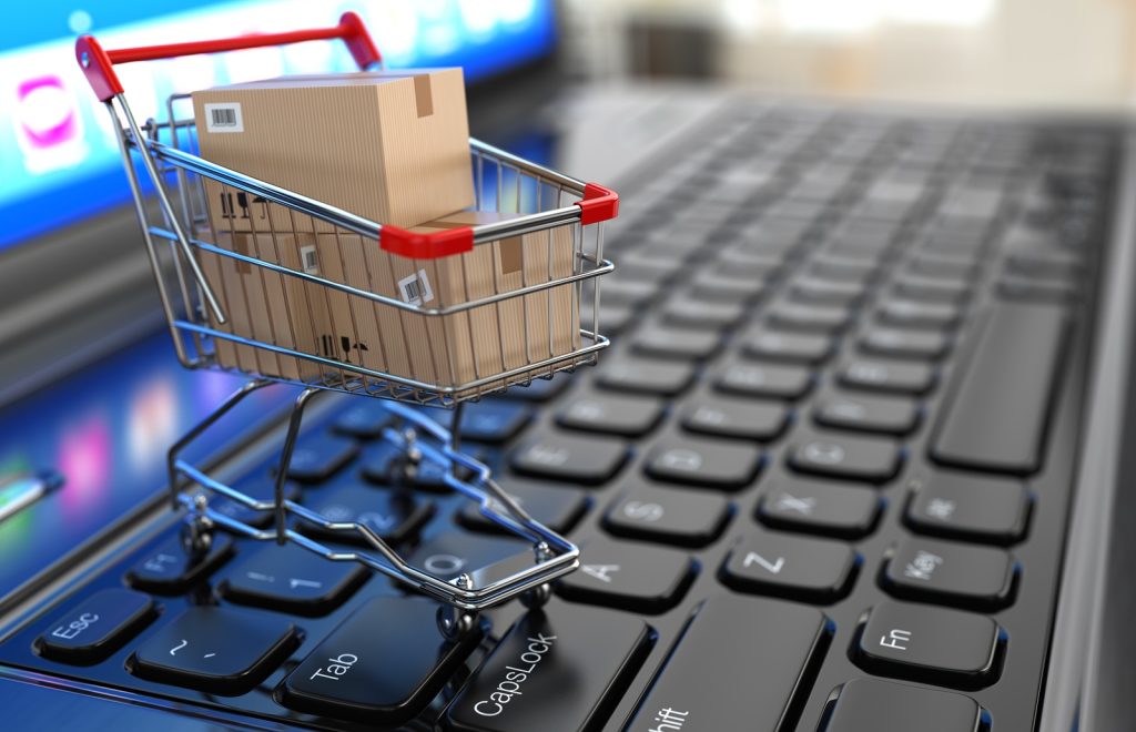 E-commerce. Shopping cart with cardboard boxes on laptop. 3d